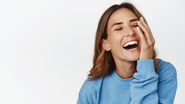 Mulher adulta sorrindo sob fundo neutro.