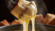 aligot sendo consumido com pedaço de pão.
