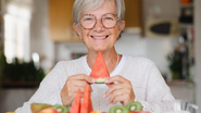 idosa se alimentando de frutas, segurando fatia de melancia