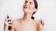 mulher sorridente aplicando body splash pós banho