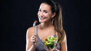 mulher sorridente segurando bowl com vegetais.