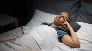 mulher deitada na cama para dormir, mas com olhos abertos, sofrendo com insônia.