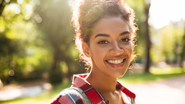 mulher sorridente em plano contraluz ao ar aberto.