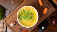 bowl com sopa proteica de frango, em cima de tábua.