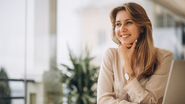 Mulher sorrindo em sua mesa de trabalho.
