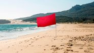 bandeira vermelha ondulando em praia.