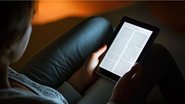 pessoa lendo no escuro, com o auxílio de seu kindle.