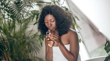 mulher com frasco de perfume na mão