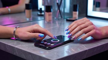 unhas que mudam de cor, ao lado de celular com aplicativo que realiza a mudança de tom.
