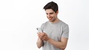 homem digitando no celular e sorrindo.