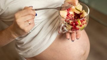 mulher grávida com bowl de alimentos em mãos