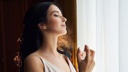 mulher aplicando perfume em seu pescoço