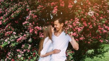 casal flertando em meio a jardim.