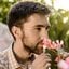 homem cheirando ramo de flores cor de rosa.