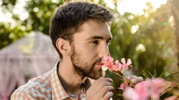 homem cheirando ramo de flores cor de rosa.