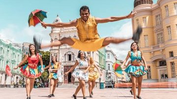 grupo de dança de frevo, com homem  saltando com guarda-chuva em mãos.
