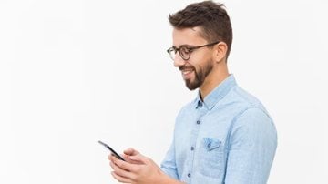 homem usando aparelho celular e sorrindo.