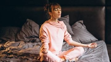 mulher meditando em sua cama antes de dormir.