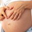 mulher grávida com as mãos sob barriga.