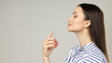 mulher fotografada de lado e borrifando perfume doce