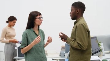 mulher e homem frente a frente, conversando, com expressões neutras.