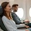 mulher sentada em poltrona de avião e sorrindo.