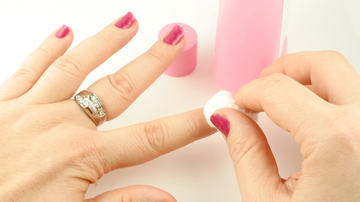 pessoa removendo esmalte das unhas com removedor.