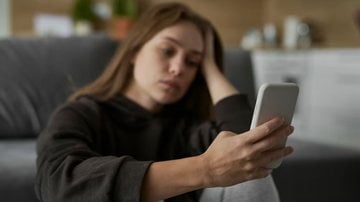 mulher triste usando o celular