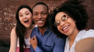 amigos fazendo selfie com expressões sorridentes.