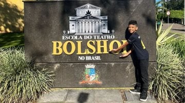 bailarino mirim em frente a placa da escola de dança