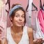 mulher escolhendo roupas com expressão de dúvida.