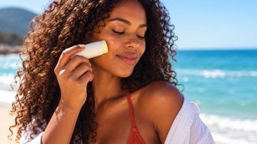 mulher aplicando protetor solar em bastão