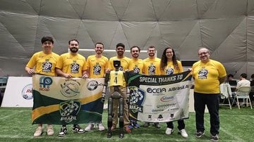 equipe brasileira posando ao lado de um dos robôs futebolistas.