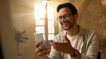 homem rindo ao ver vídeo no celular.