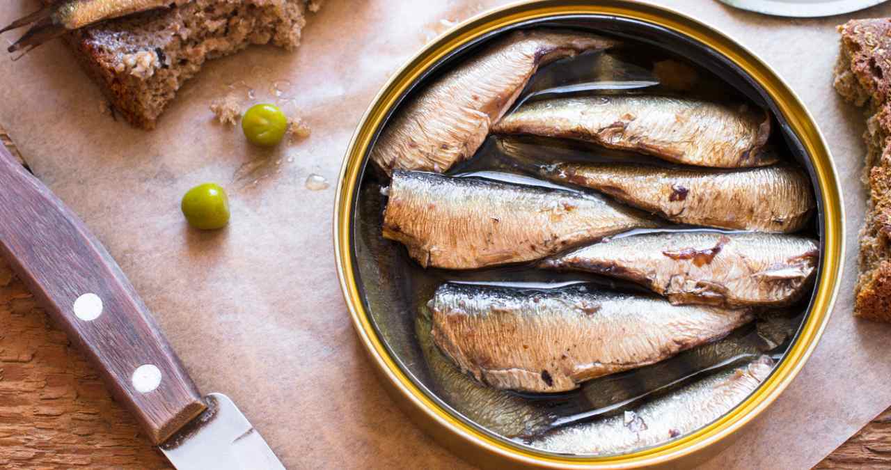 sardinhas temperadas dentro de uma panela que se encontra sobre uma mesa de madeira