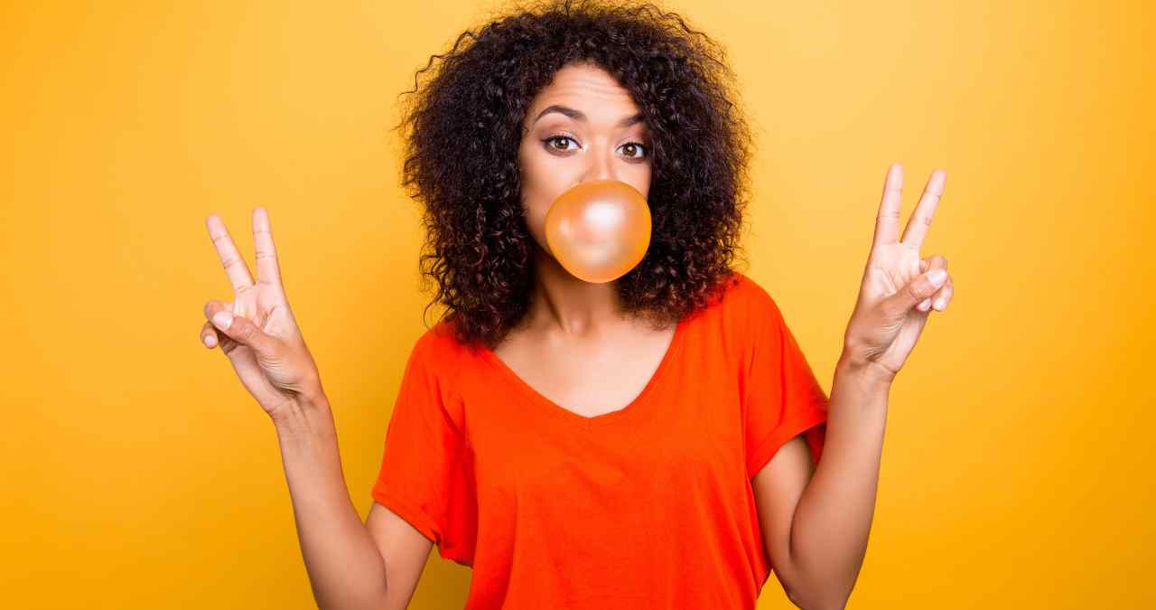 uma modelo posando para câmera enquanto faz uma bola de chiclete