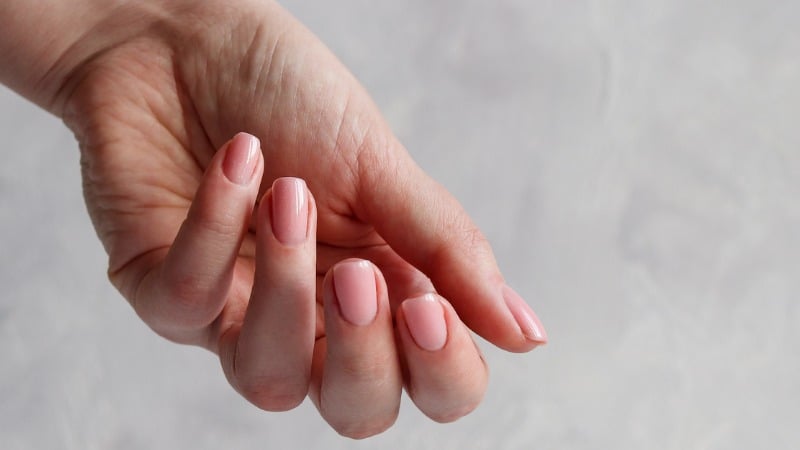 Unhas pintadas com esmalte de cor nude.