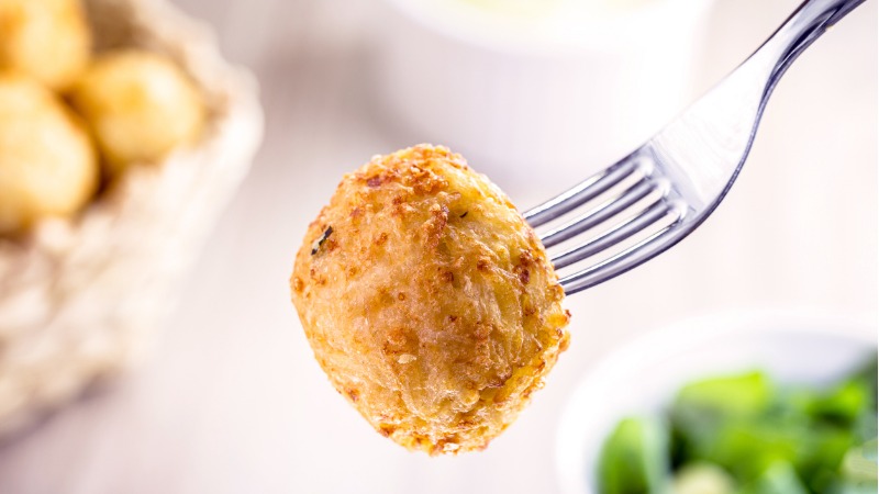 Bolinho de arroz espetado em garfo.