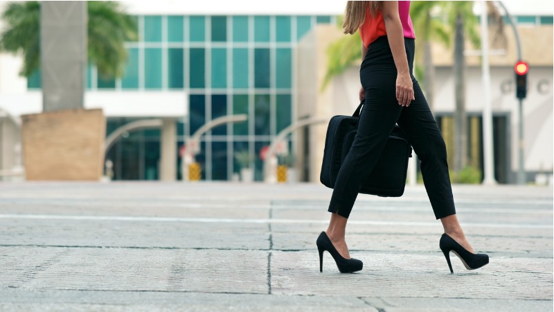 Mulher vestindo preto caminhando para a direita.