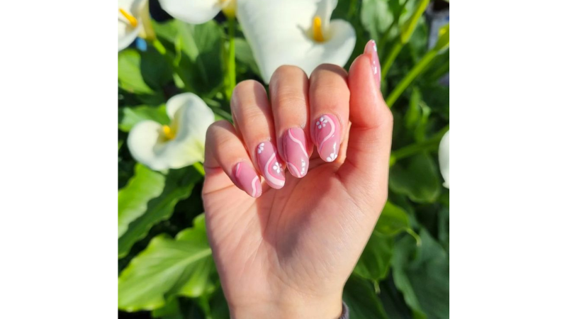 Unhas rosa com aplicações florais.