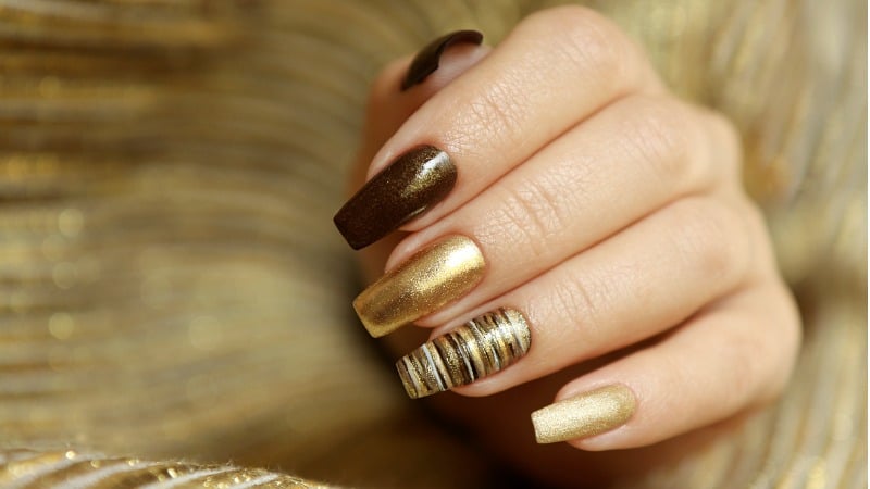 Unhas decoradas com esmalte dourado em diferentes tipos de textura.