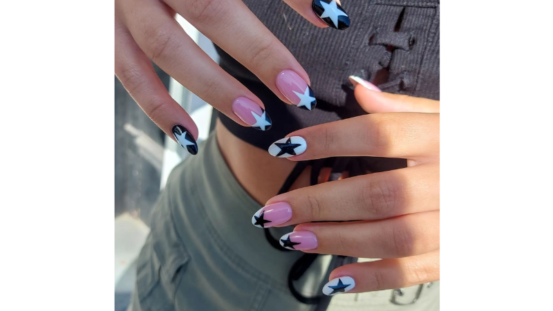 Unhas decoradas em preto e branco com estrelas.