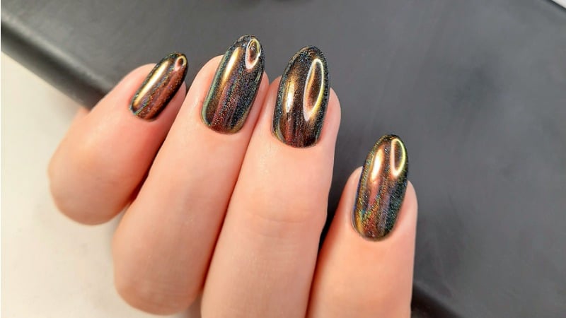 Unhas douradas com acabamento iridescente.