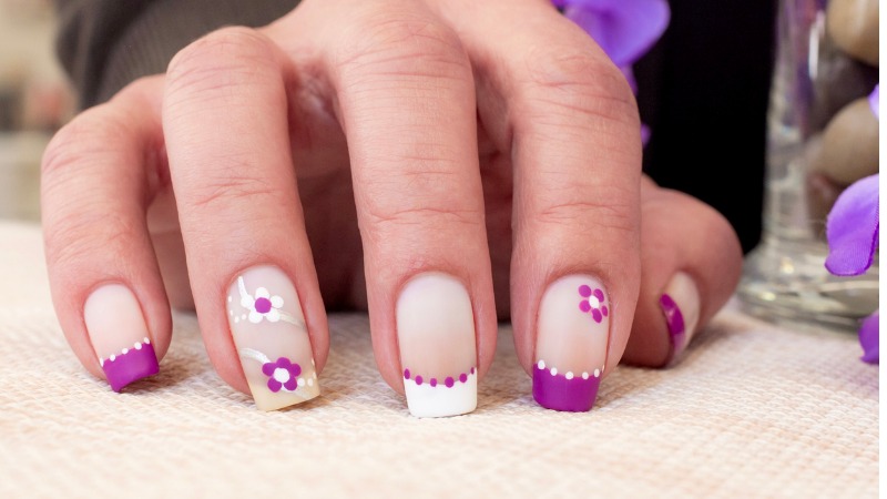 Unhas lilás decoradas com pétalas de flores