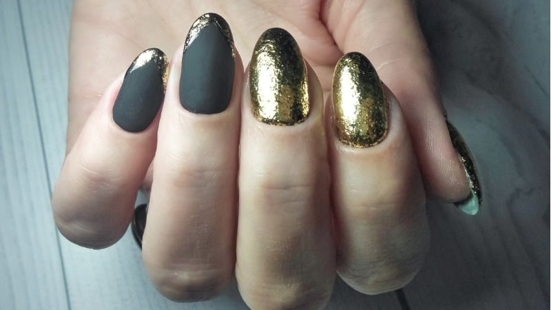 Unhas pretas com decorações em dourado.