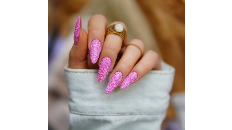 Unhas decoradas totalmente com glitter rosa.