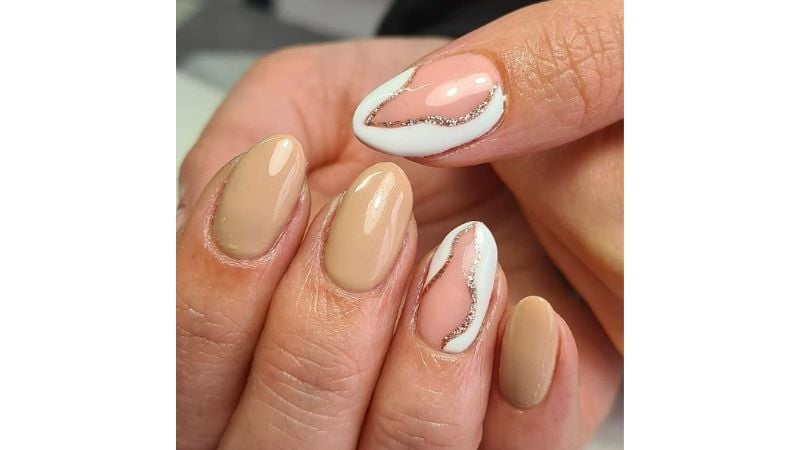 O esmalte marrom em tom aberto é uma das principais tendências deste ano. Uma boa escolha para compor a estética com unhas brancas e glitter!