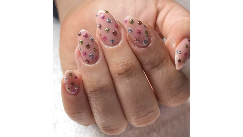 Unhas nude decoradas com glitter.