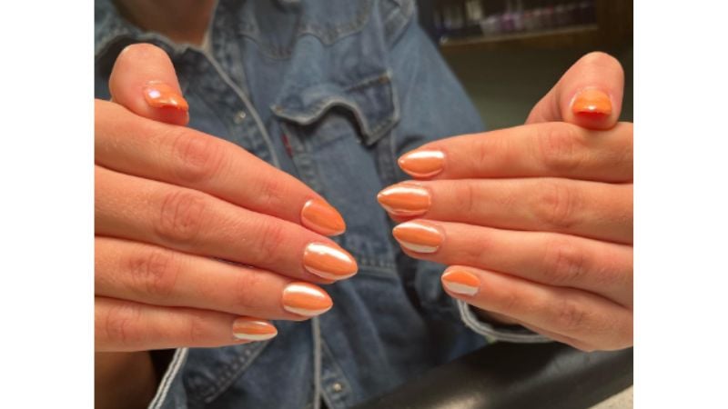 Unhas metalizadas são uma das principais tendências de 2023. Investir nessa nail art com o esmalte laranja é uma ótima ideia.