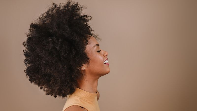 mulher negra sorrindo para o lado direito da câmera